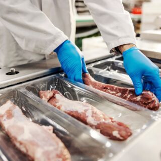 Close,Up,Of,Hands,Packing,Meat,With,Vacuum,Heat,Sealing