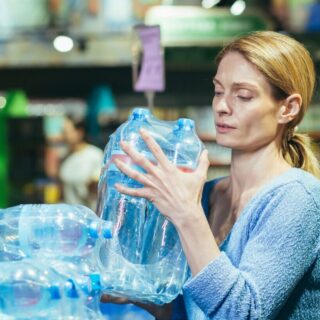 A,Woman,Buys,Pallets,Of,Water,In,A,Supermarket.,Packs